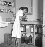 Mary Uyesato, a trained medical laboratory assistant, at work in the medical center at the Manzanar Relocation Center for deported Japanese-Americans, Inyo County, California, United States, 3 Jul 1942.