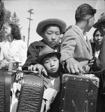 Young Japanese-American evacuees waiting their turn for baggage inspection at the Assembly Center in Turlock, California, 2 May 1942.