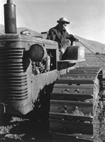 Benji Iguchi on a tractor in the agricultural fields at the Manzanar Relocation Center for deported Japanese-Americans, Inyo County, California, United States, 1943.
