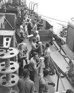 All hands passing 5-inch powder casings aboard USS Nicholas alongside an ammunition barge at Tulagi, Solomon Islands, Aug 1943.
