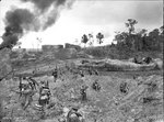 A Company of the Australian 2/23 Infantry Battalion advancing through wrecked oil storage tanks at tank hill, Tarakan, 1 May 1945
