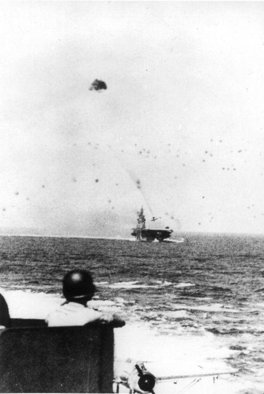 Anti-aircraft crew member of USS New Jersey watching a special attack aircraft diving into USS Intrepid, 25 Nov 1944; note OS2U Kingfisher float plane on the port catapult