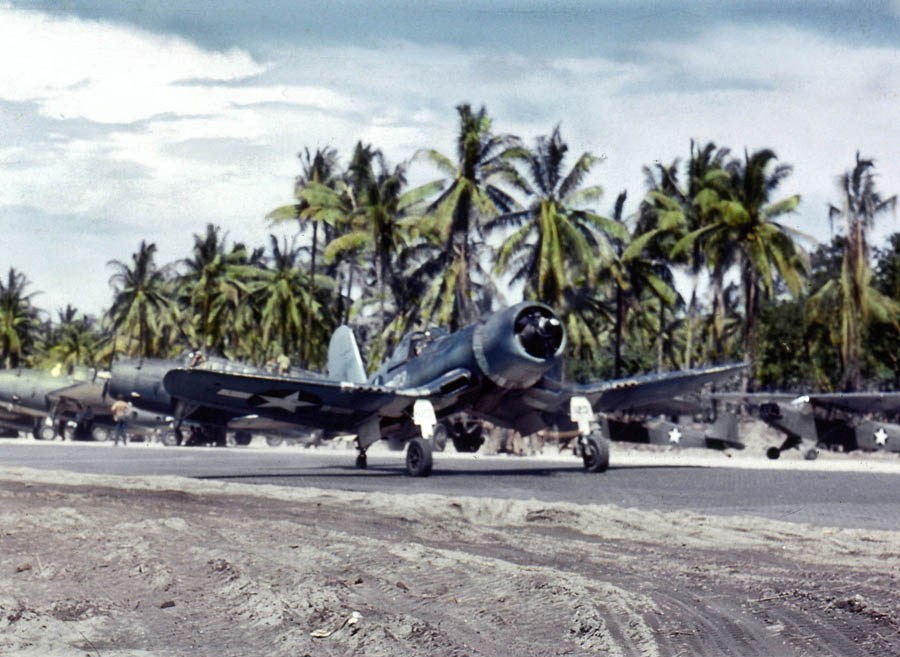 F4U-1A Corsair of Marine Squadron VMF-216 taxis down the strip at Torokina, Bougainville, Solomon Islands, Dec 1943. Note TBM Avengers and NE-1 Grasshoppers parked along the strip.