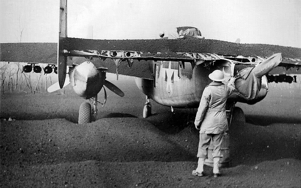 Crew member examining a layer of ashes on a B-25 of the 340th Bomb Group at Pompeii Field, Italy. Ash came from an eruption of Mt Vesuvius on 23 Mar 1944 that rained hot ash and brimstone on the area damaging several aircraft. Photo 2 of 2.