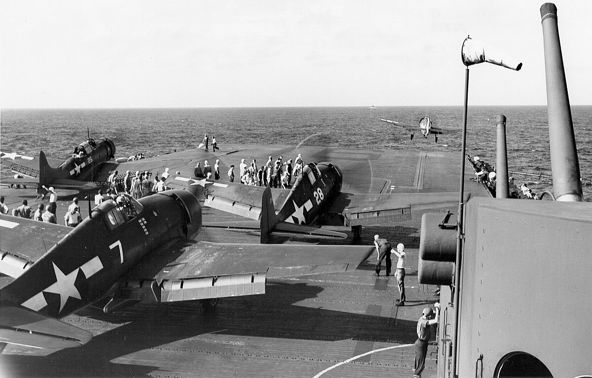 F6F Hellcat of VF-16 launches from the carrier Lexington (Essex-class) while two others wait along with an SBD Dauntless, 1943-44.