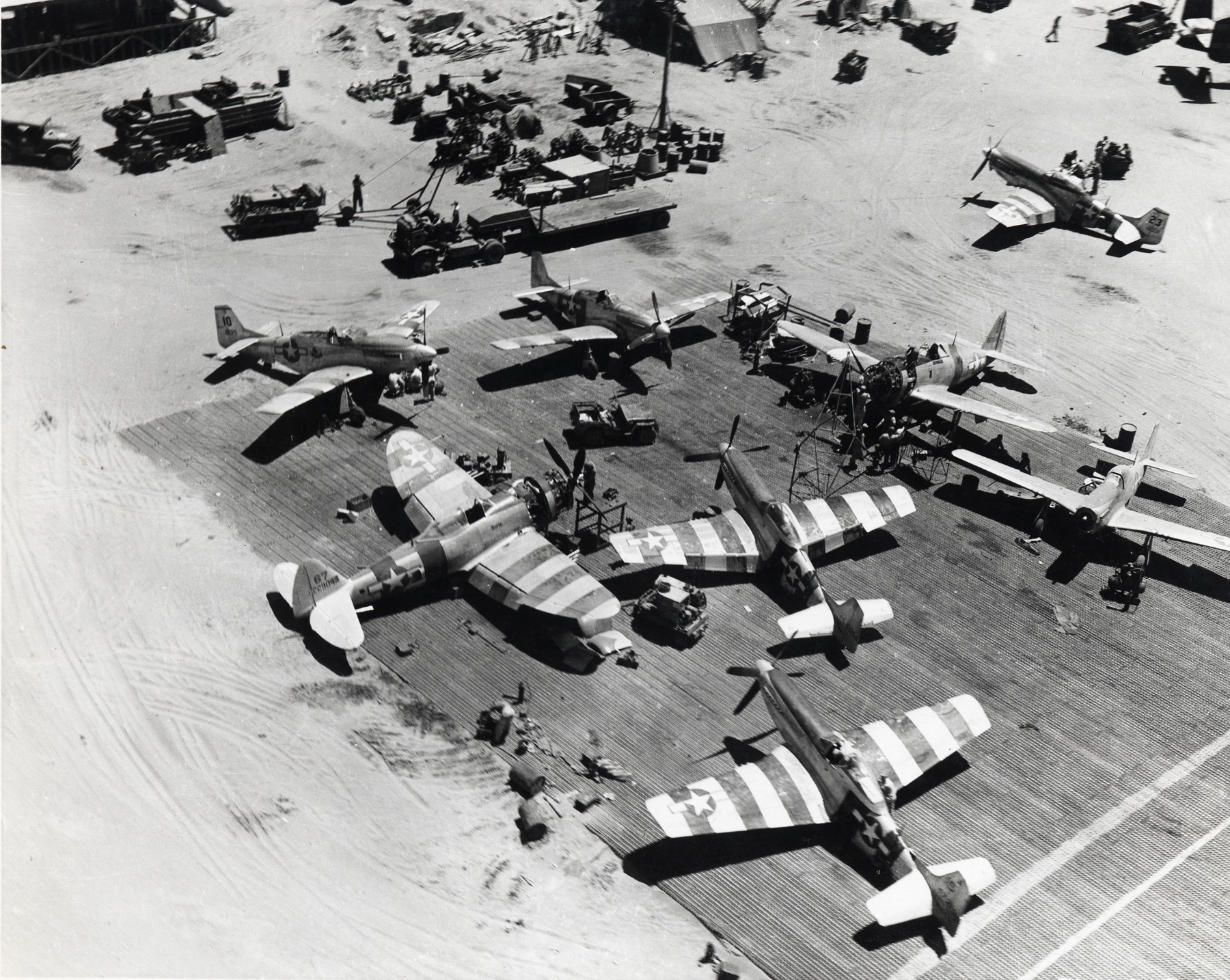 Maintenance area servicing P-51 Mustangs and one P-47 Thunderbolt of the 35th Fighter Group, Lingayen Airfield, Luzon, Philippines, Apr 1945