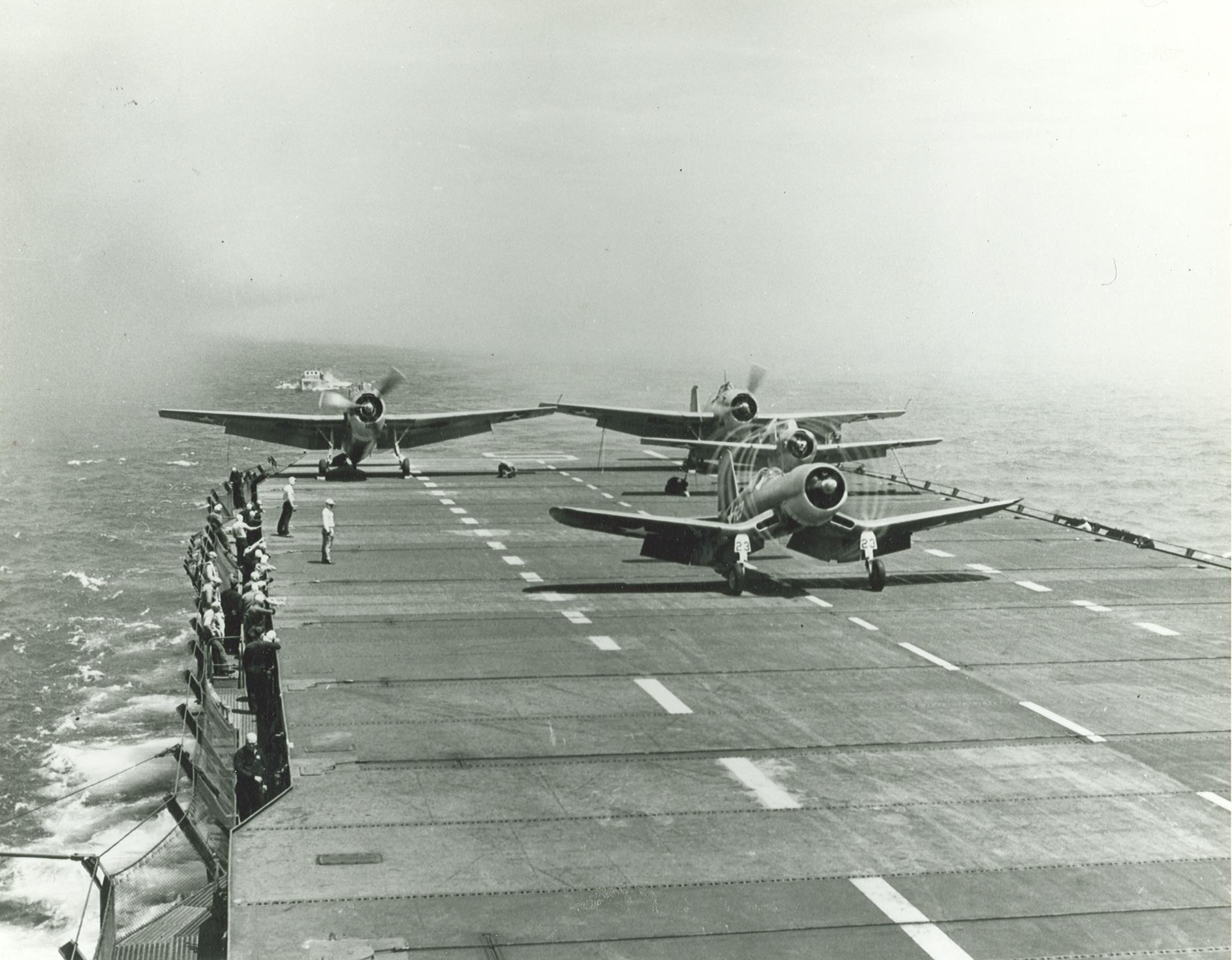 F4U-1 Corsair, an F4F Wildcat, and two TBF-1 Avengers run up their engines prior to launch from the training aircraft carrier USS Sable on Lake Michigan, United States, mid-1943.