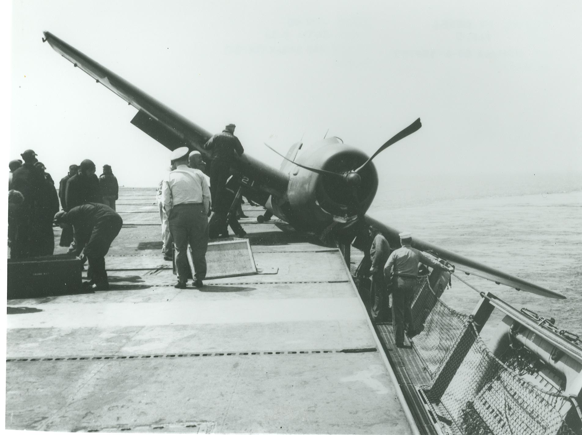 A Grumman F6F Hellcat with one wheel in the catwalks aboard the training aircraft carrier USS Wolverine on Lake Michigan, United States, 1945. Note the severely bent propeller blades.