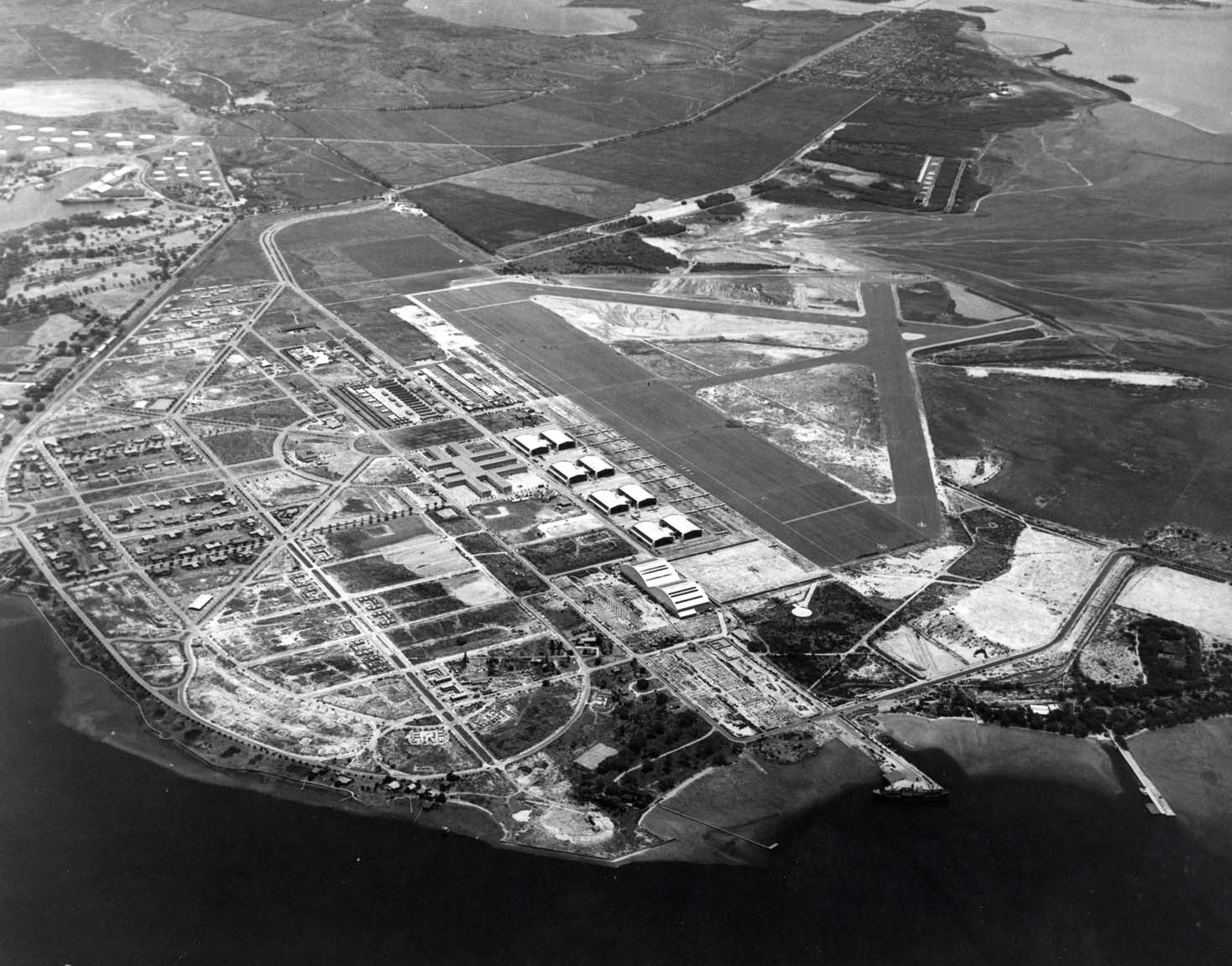 Aerial view of Hickam Field looking toward Honolulu, Hawaii, 3 May 1940. The Pearl Harbor entrance channel is along the bottom of the photo and the Submarine Base can be seen at the upper left.