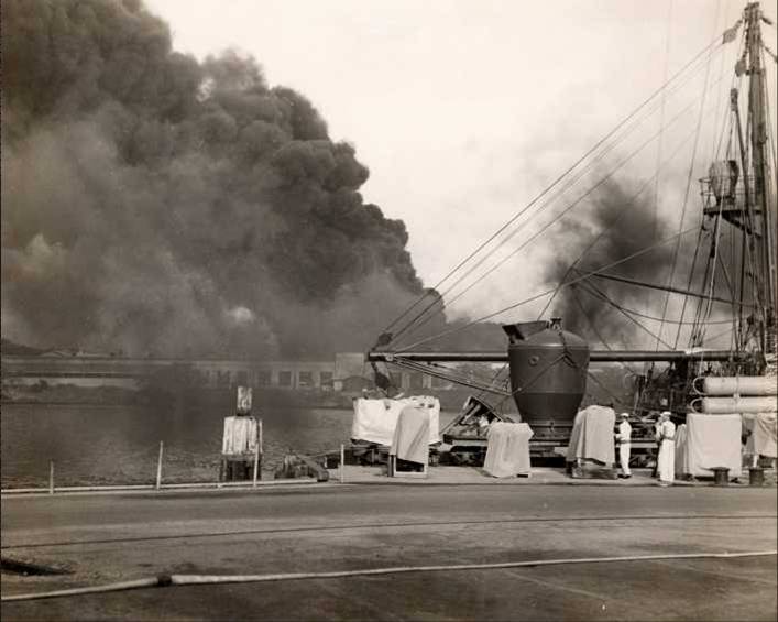 Smoke from Battleship Row rises from behind the Supply Depot as seen from the Submarine Base, Pearl Harbor, Oahu, Hawaii, Dec 7, 1941.
