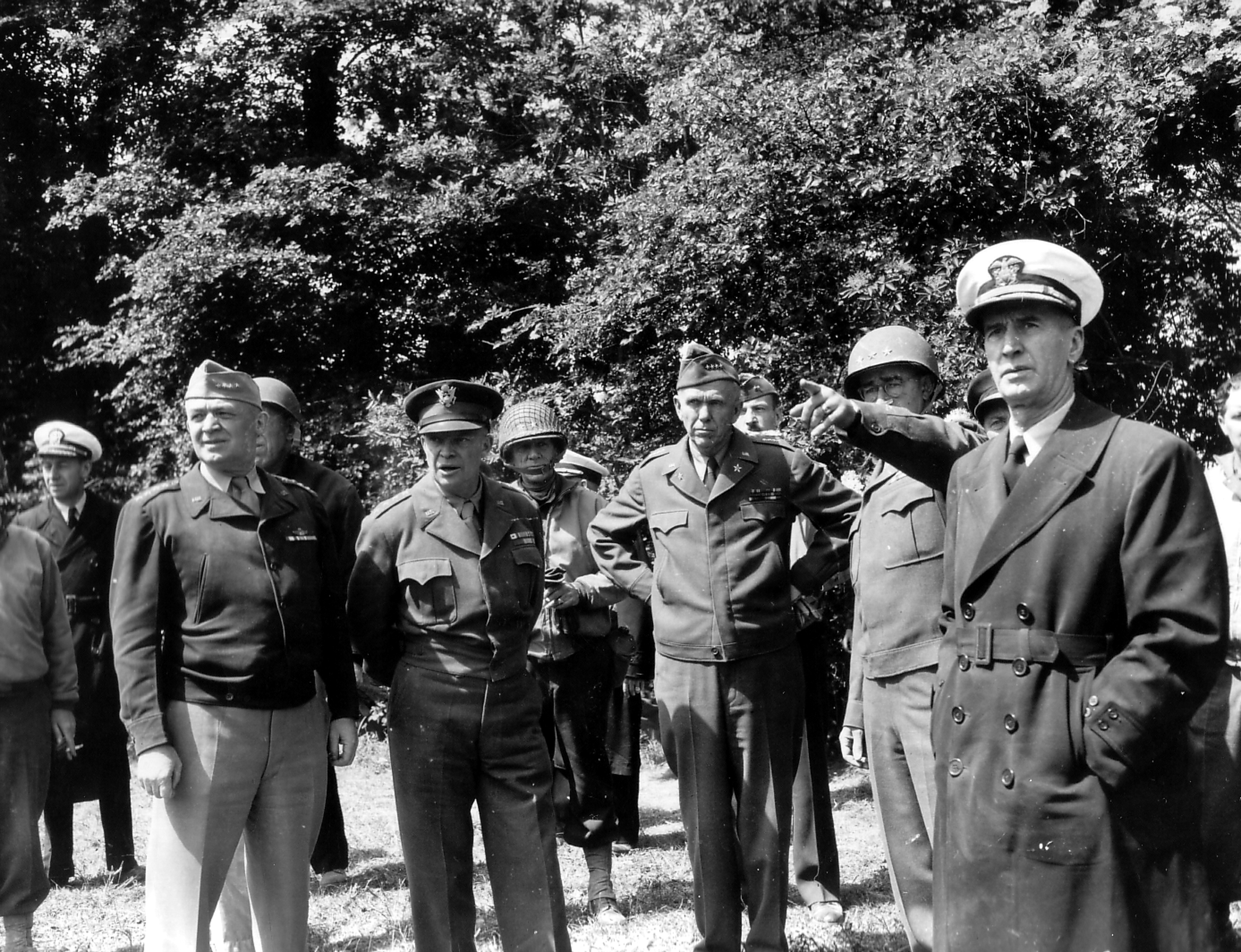 Gen “Hap” Arnold, Gen Dwight Eisenhower, MajGen “Cowboy Pete” Corlett (helmet), Gen George Marshall, LtGen Omar Bradley (pointing), and Adm Ernest King visit the guns moved from Pt du Hoc, Normandy, France, Jun 12, 1944.