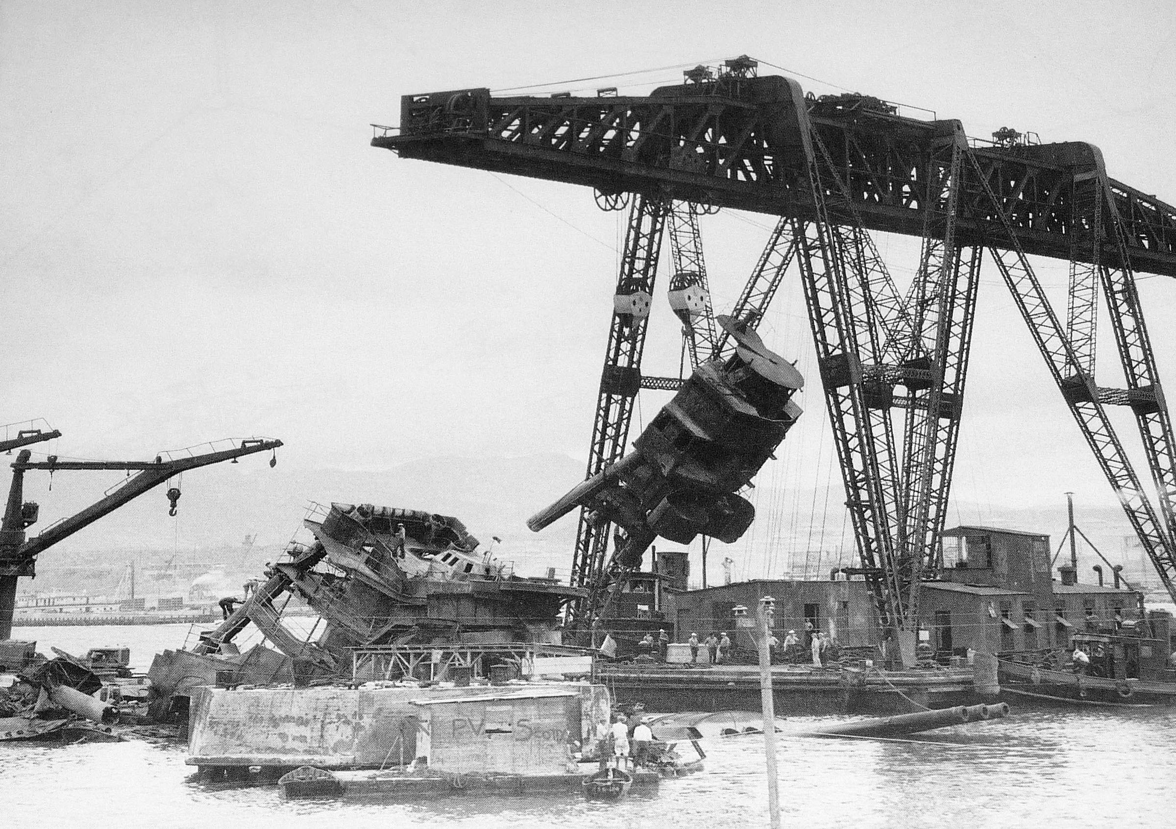 Floating crane YD-25 raising USS Arizona’s foremast during salvage operations in Pearl Harbor, Oahu, Hawaii, circa 1943. Note the guns of Arizona's No. 2 turret rising out of the water.