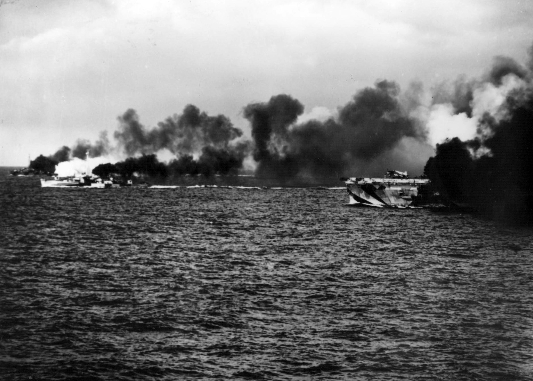 Escort Carrier USS Gambier Bay, Destroyer Escort USS Raymond, and another Destroyer Escort, elements of Taffy 3, laying smoke before engaging the Japanese Center Force in the Battle Off Samar, Oct 25, 1944.