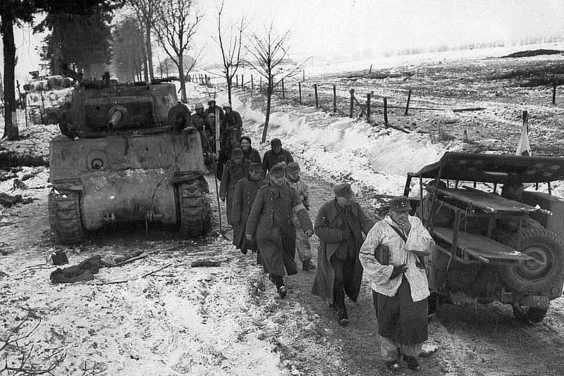 German prisoners of war marching between a disabled M4 Sherman tank and a litter-Jeep, Jan 1945. This is possibly during the Battle of the Bulge but more likely is the Battle of Hürtgen Forest.