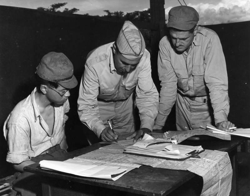 LtCol LF Maybach, with pen, completing paperwork relating to Japanese POW 2Lt Minoru Wada, seated, Aug 7, 1945, Libby Field, Davao, Mindanao, Philippines.