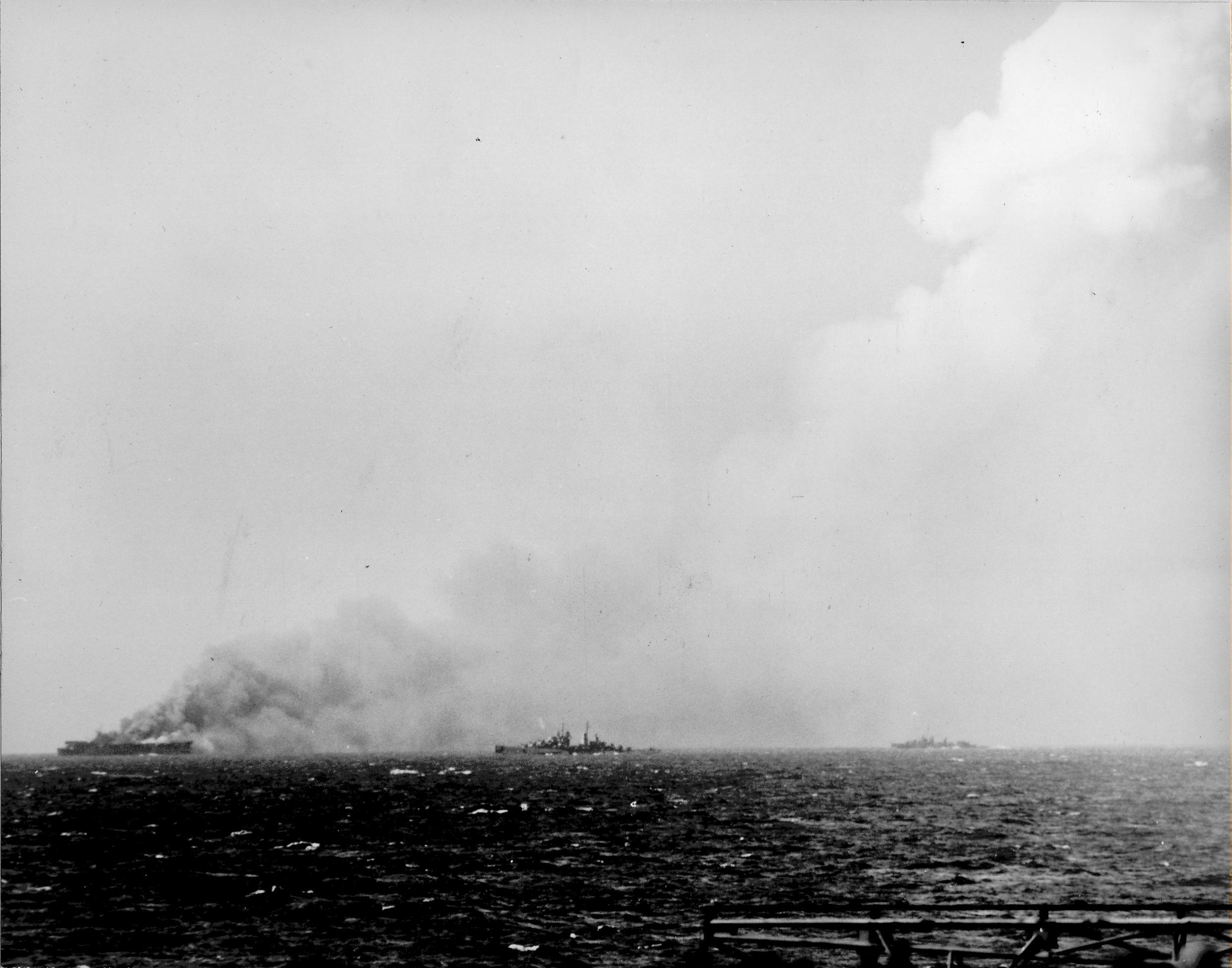 Badly damaged carrier USS Princeton burns as cruiser Reno and destroyer Morrison close in to offer assistance, 24 Oct 1944 as seen from USS Essex off Luzon in the Philippines.