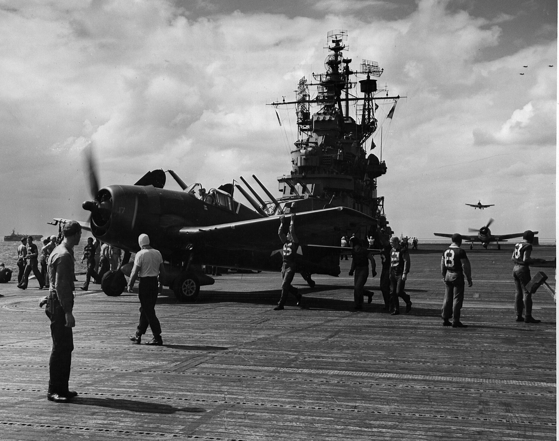 USS Lexington (Essex-class) flight deck personnel spotting one F6F-5 Hellcat that has just landed as next one taxis forward and next one is about to land, all returning from raids on the Ryukyu Islands, 10 Oct 1944