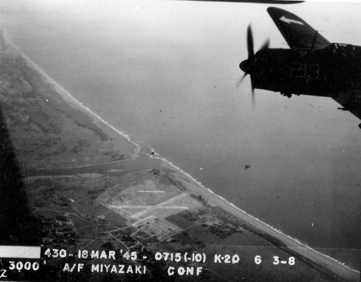 Strike photo taken by aircraft from USS Bunker Hill showing an SB2C Helldiver from Bombing Squadron VB-84 over Miyazaki Airfield on southern Kyushu, Japan, 17 Mar 1945