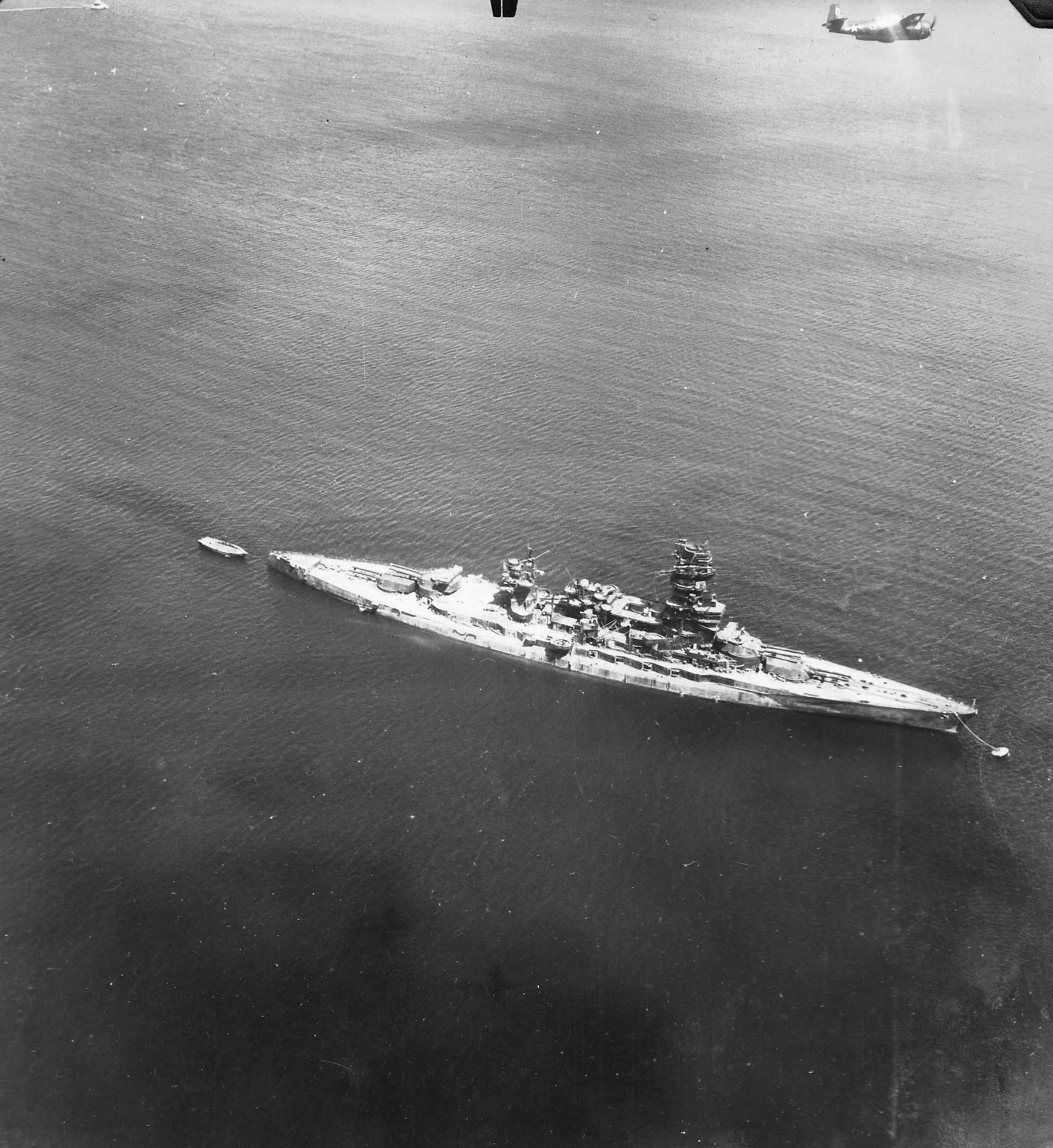 Post-war photo of a TBM-3 Avenger from Torpedo Squadron VT-27 from the aircraft carrier USS Independence flying over the Japanese battleship Nagato at Yokosuka, Japan, Aug-Sep 1945