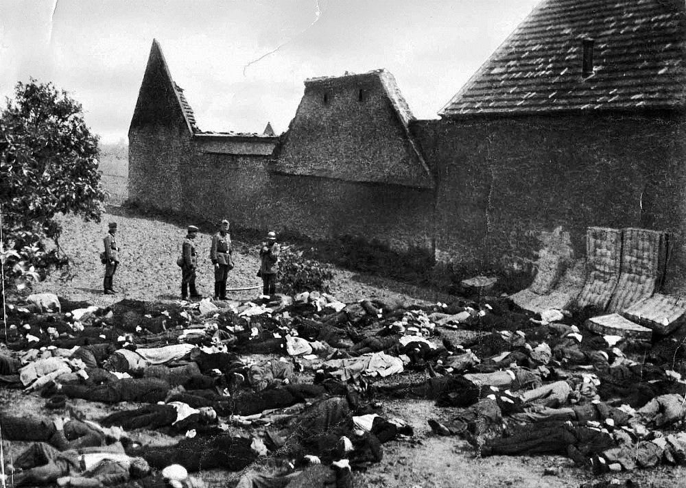 Lidice, Czechoslovakia 10 Jun 1942. SS officer standing over the bodies of all 173 of the village’s men in the garden at the Horák family farm. The mattresses were put up against the stone wall to prevent ricochets.