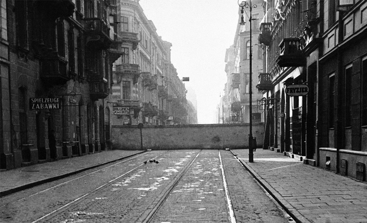 A freshly-constructed wall across a street in the city center defines the boundary of the Warsaw Ghetto for the city’s approximately 500,000 Jews, 20 Dec 1940.