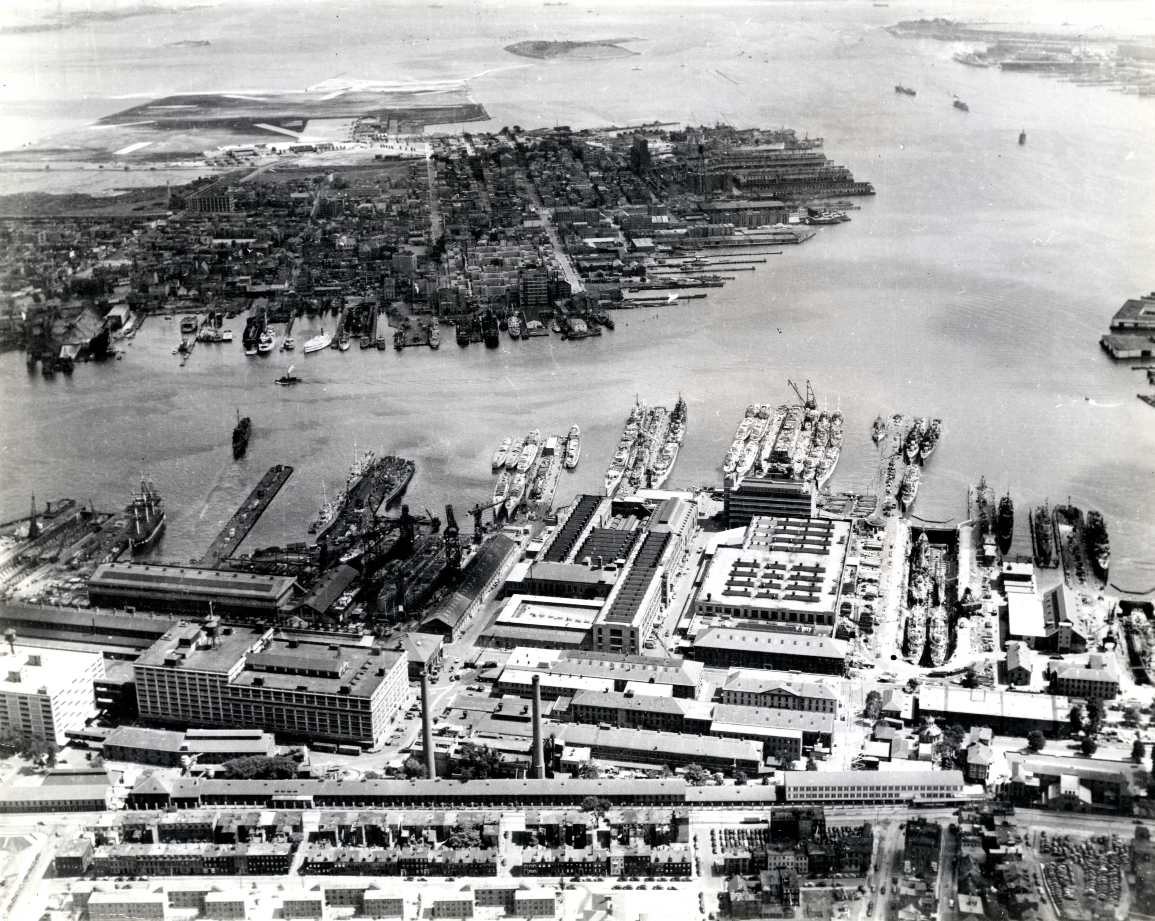 Aerial view of Boston Navy Yard, Boston, Massachusetts, United States, 1942; note frigate USS Constitution at left and Jeffrey Field (now Logan International Airport) in background