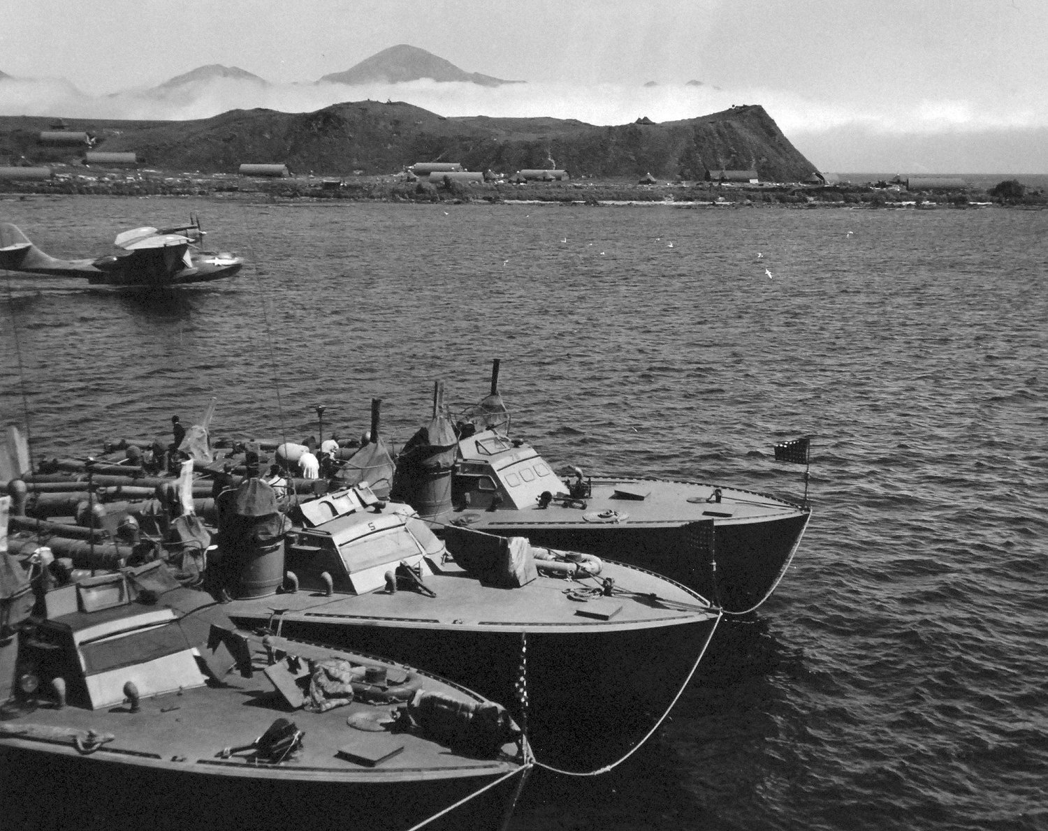 Higgins 78-foot torpedo boats of Motor Torpedo Boat Squadron 13 (MTBRon 13) moored in Attu, Alaska, Jul 943. Note PT-75 and PT-78 nested outboard of their squadron-mate and PBY Catalina patrol plane taking off.