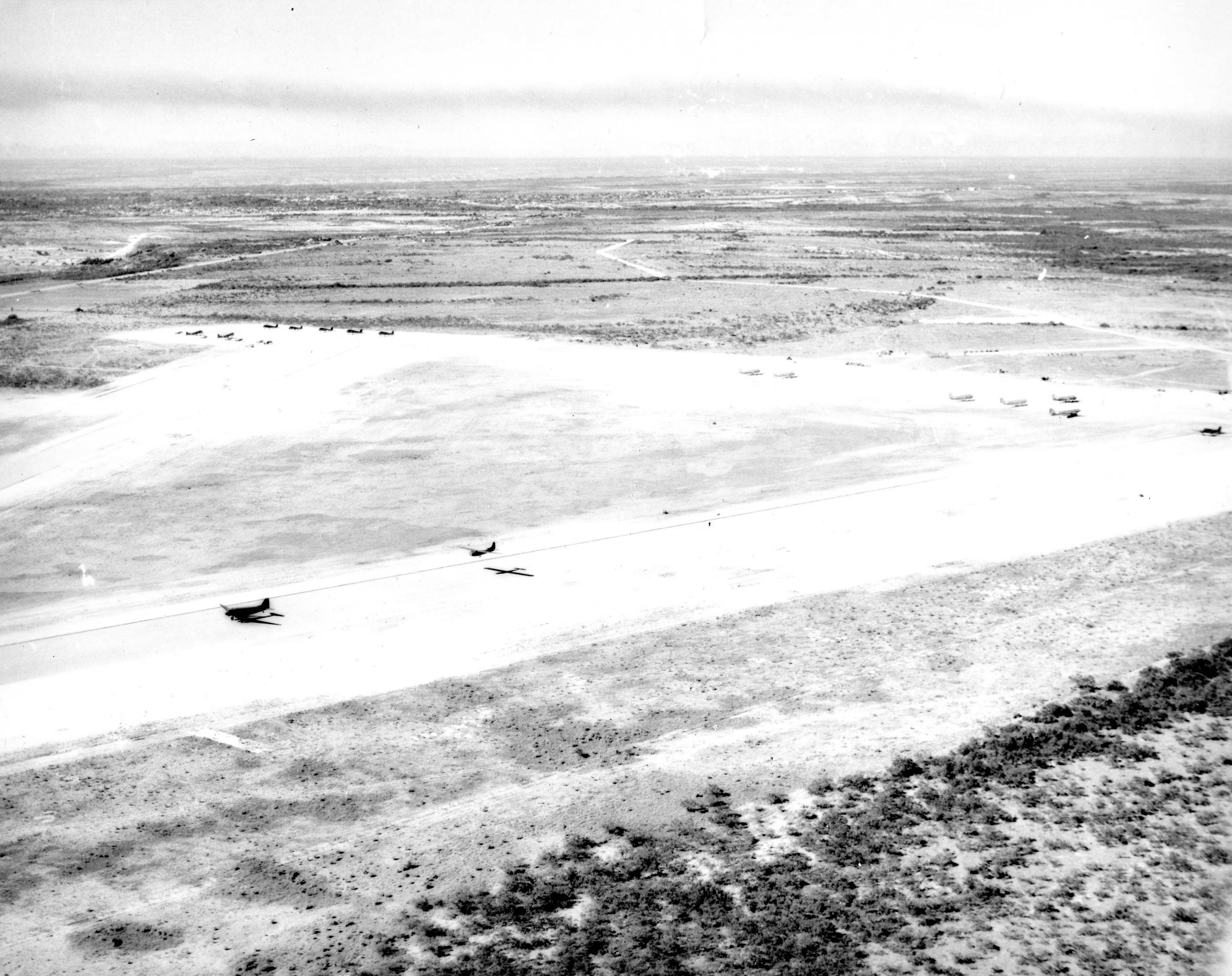 Aerial view of a glider training airstrip in Texas, 1943. Visible are C-47 Skytrain tow planes with Waco CG-4A gliders. Note the CG-4A in tow taking off.