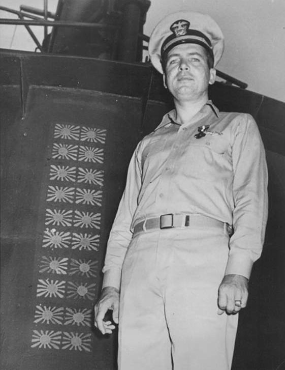 Lieutenant Commander Roy Davenport posing beside USS Haddock's conning tower, 10 Nov 1943