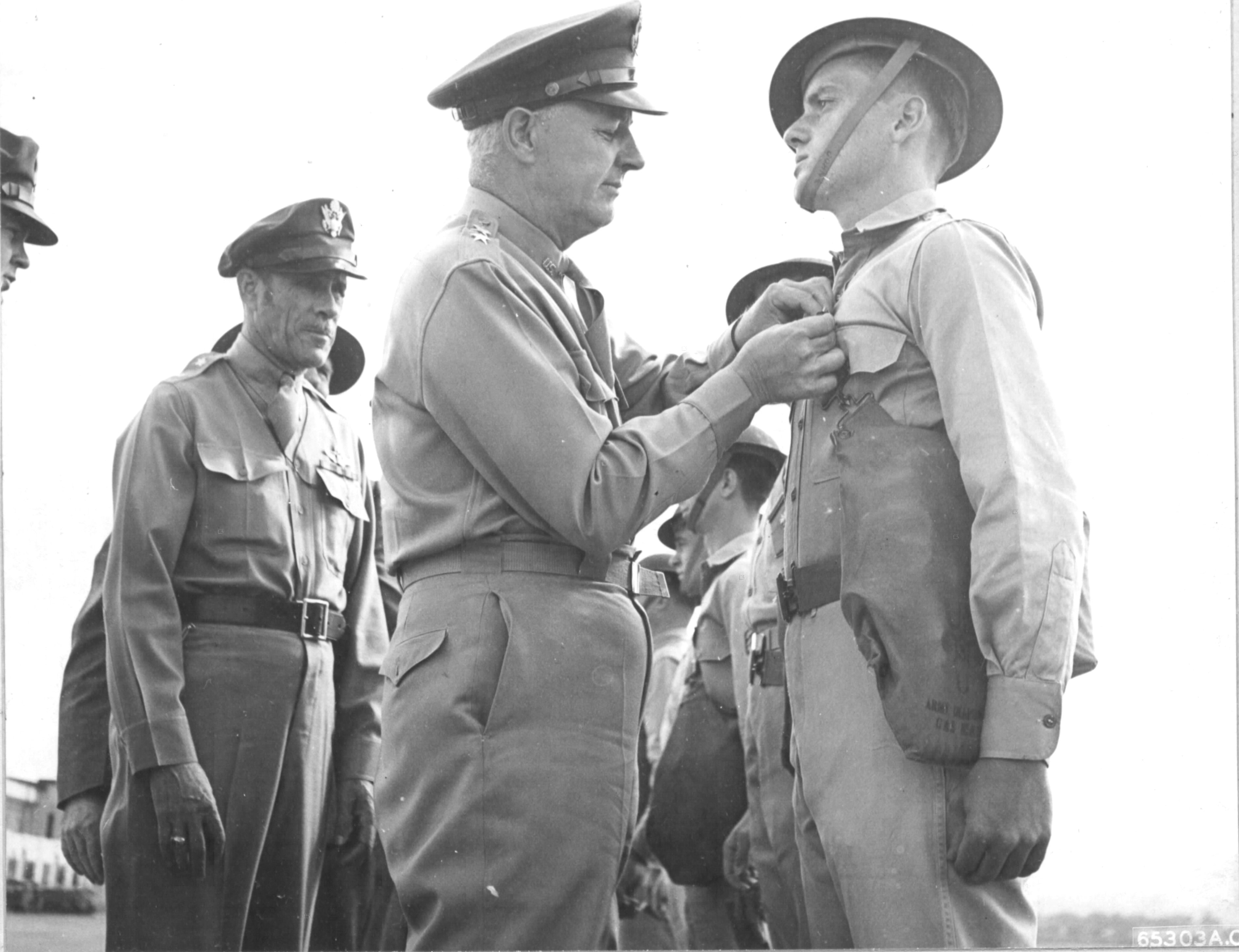 Lieutenant General Delos Emmons decorating an enlisted man for actions performed during the Japanese attack on Pearl Harbor. Hickam Field, 23 Dec 1941. Major General Clarence Tinker looking on.