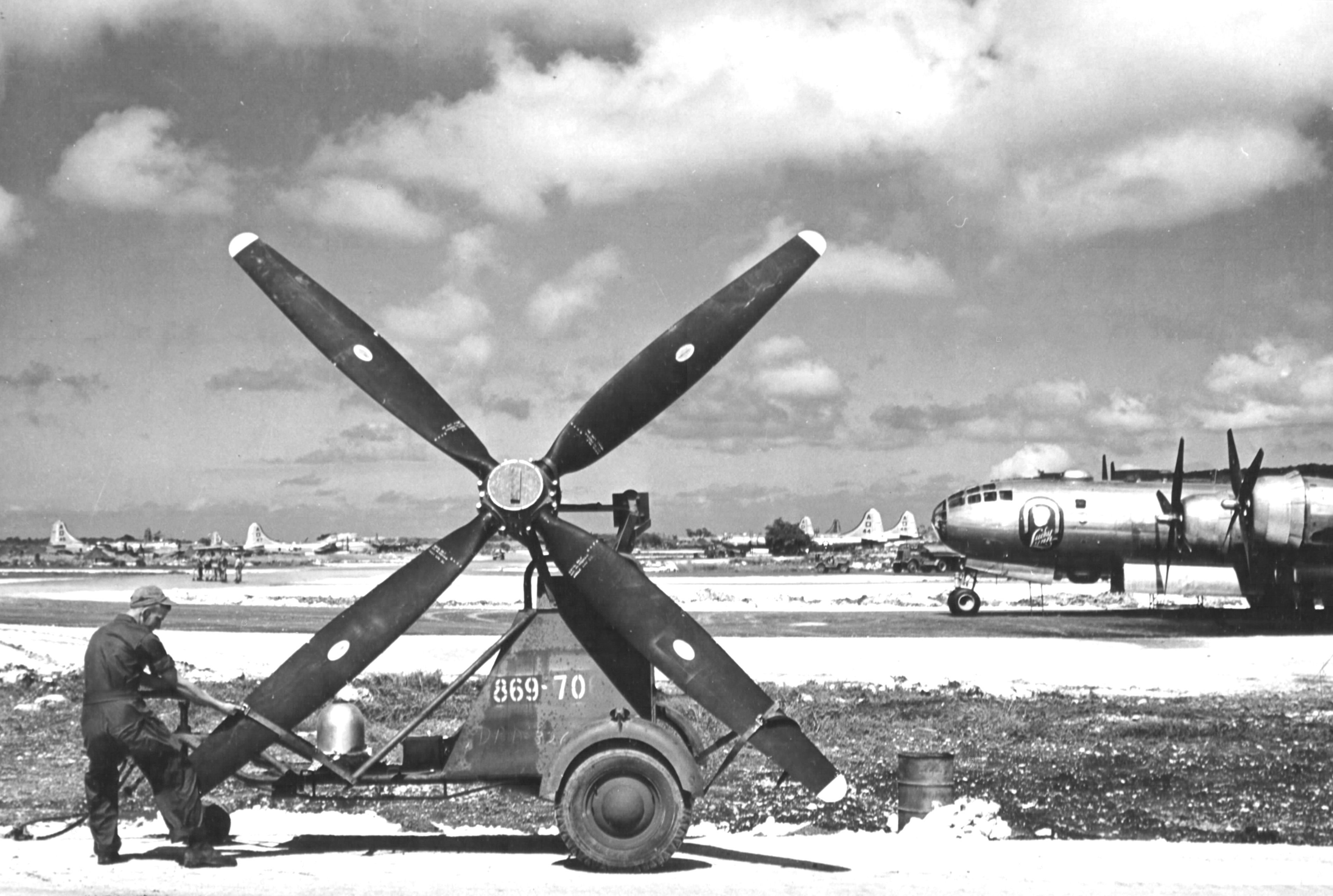 An aircraft maintenance crewman with the 497th Bomb Group at Isley Field on Saipan, Mariana Islands securing a propeller for a B-29 Superfortress to a service trailer, late 1944. Note B-29 “Lucky Lynn” beyond.