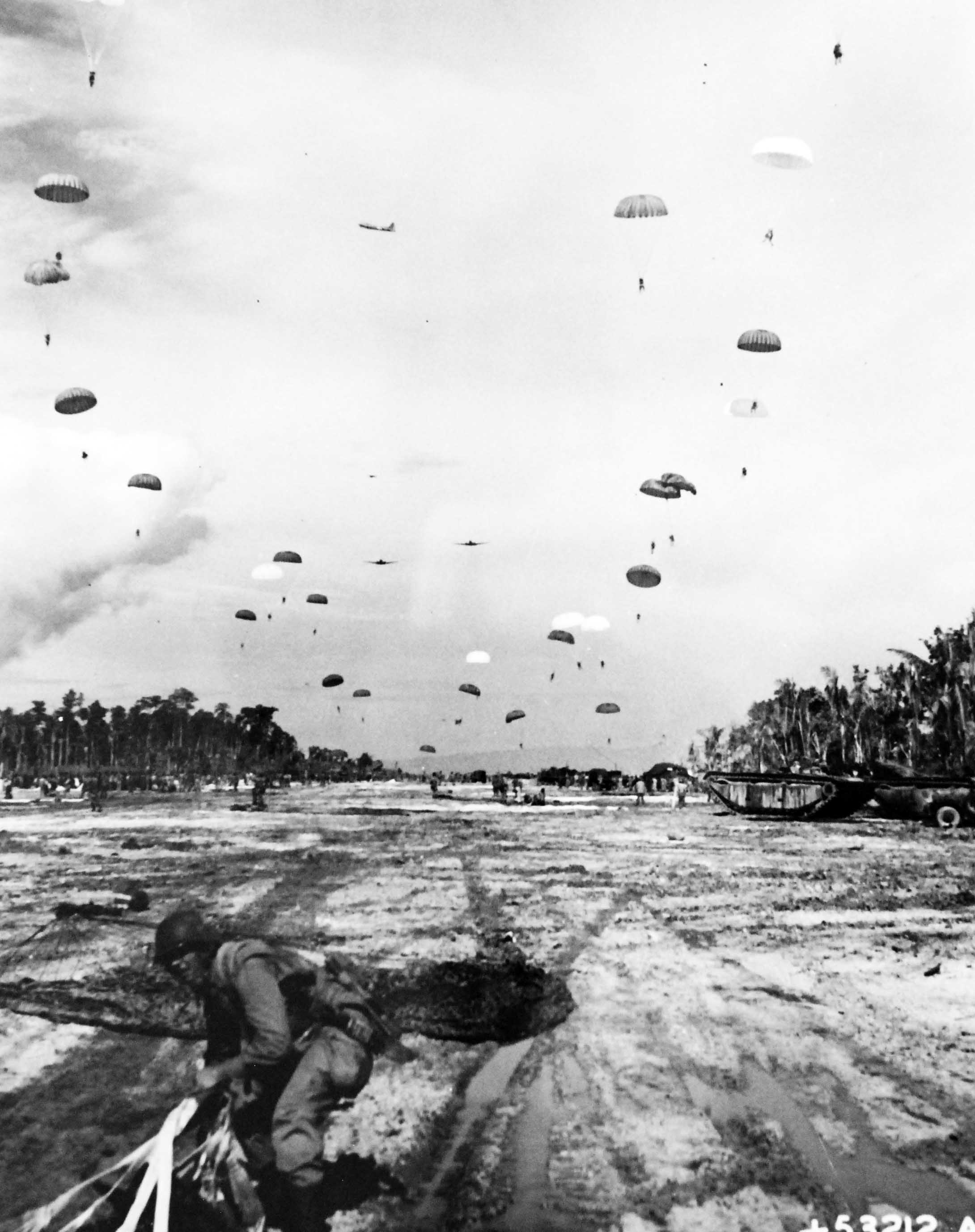United States Army paratroopers landing on the Kamiri airstrip on Noemfoor Island off New Guinea, 3 Jul 1944. Note B-17 fortress patrolling high overhead.