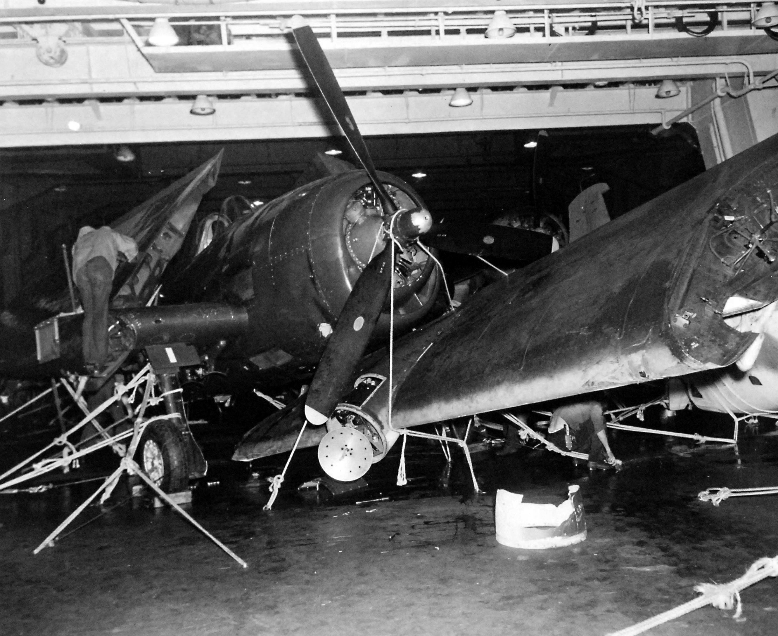 Damaged aircraft on the hangar deck of the USS Independence, 6 Oct 1944 following heavy seas 3 days earlier. Note the hand-tied rope lashings to secure the aircraft. Note also the AIA radar antenna in the damaged radome