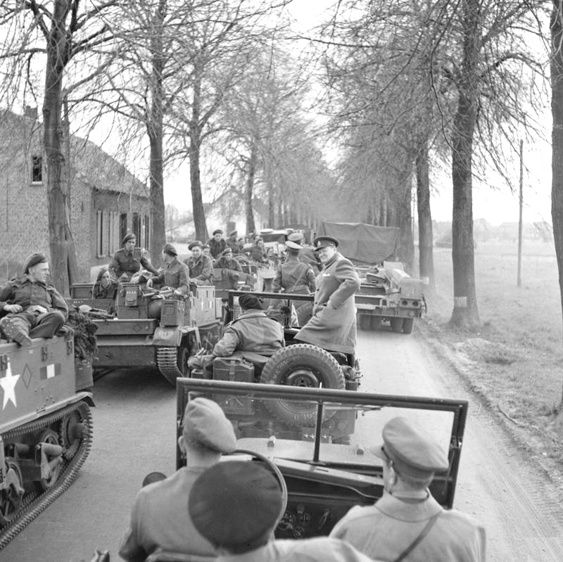 During their tour of the assault on the Rhine, British Prime Minister Winston Churchill and Field Marshal Bernard Montgomery stopped their Jeeps to allow troops to pass in troop carriers, 26 Mar 1945.