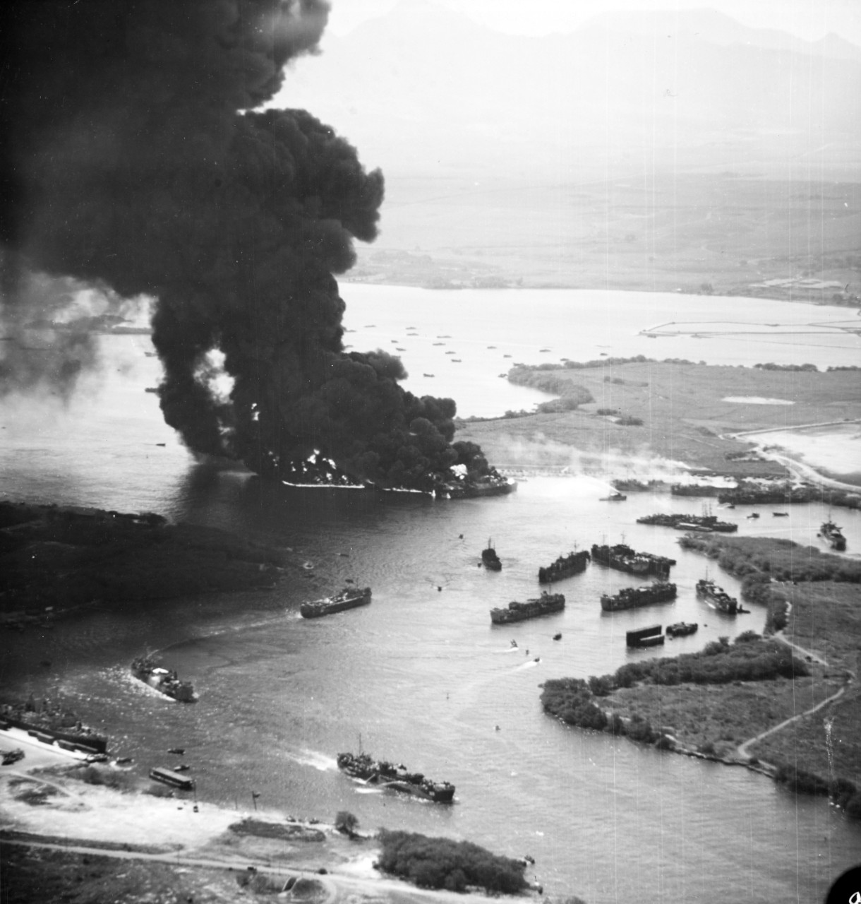 Fully laden United States Navy LSTs burning furiously while other ships flee in Pearl Harbor’s West Loch after massive chain-reaction explosions in what became known as the West Loch Disaster, 21 May 1944.