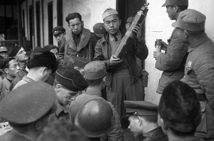 Chinese officer displaying captured Japanese chemical canisters to journalists, Changde, Hunan Province, China, 25 Dec 1943