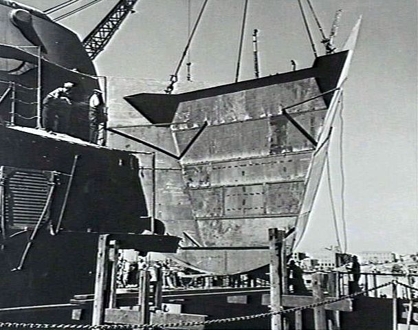 USS New Orleans in the Cockatoo Docks in Sydney, Australia as a temporary bow is being lowered into place after she was struck by a torpedo in the Battle of Tassafaronga that blew off 150 feet of her bow.