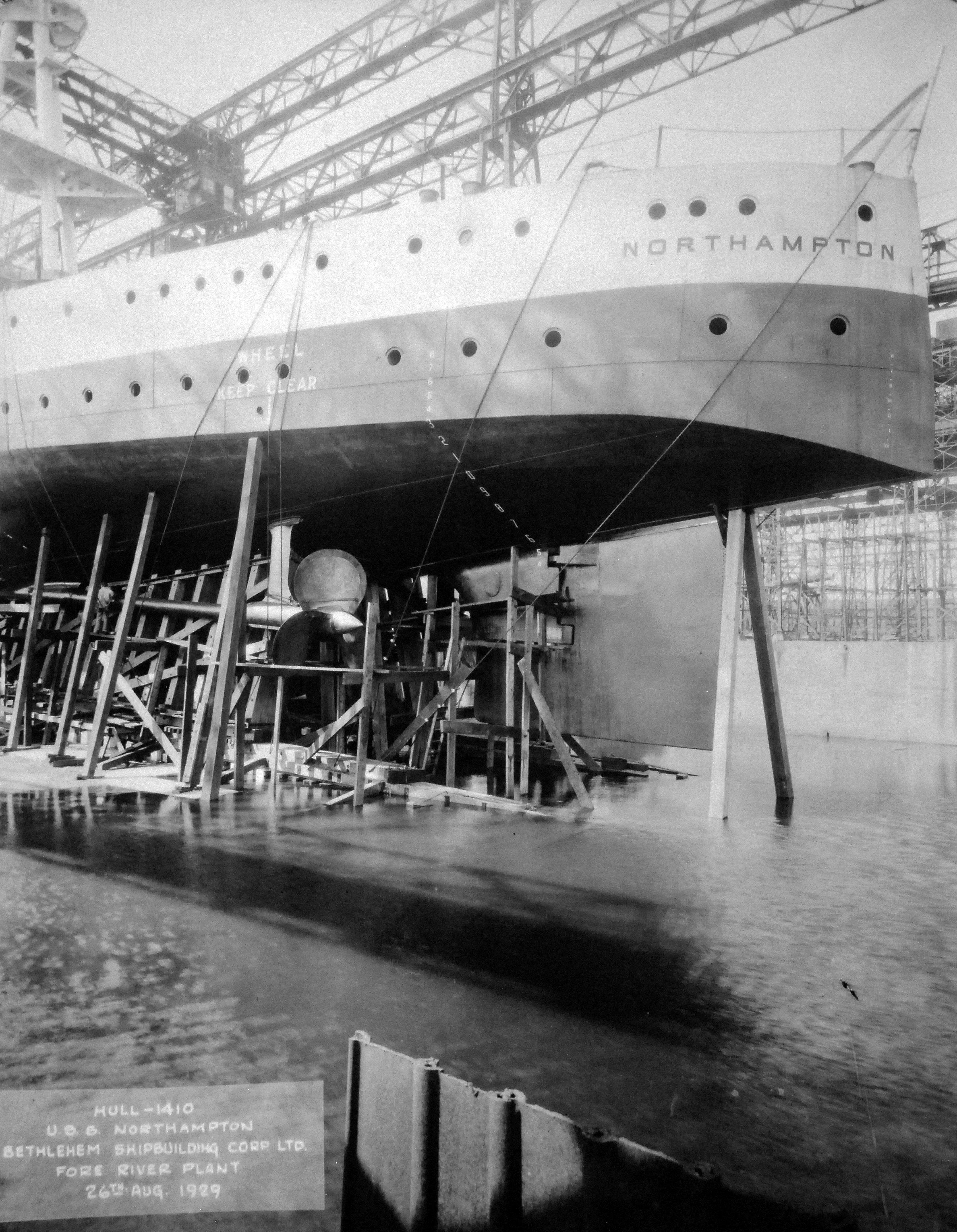 Screws and stern of the cruiser Northampton on the ways ten days before her launching, Bethlehem Steel Fore River Shipyard in Quincy, Massachusetts, United States, 26 Aug 1929. Note the man standing on the scaffold next to the propeller shaft.