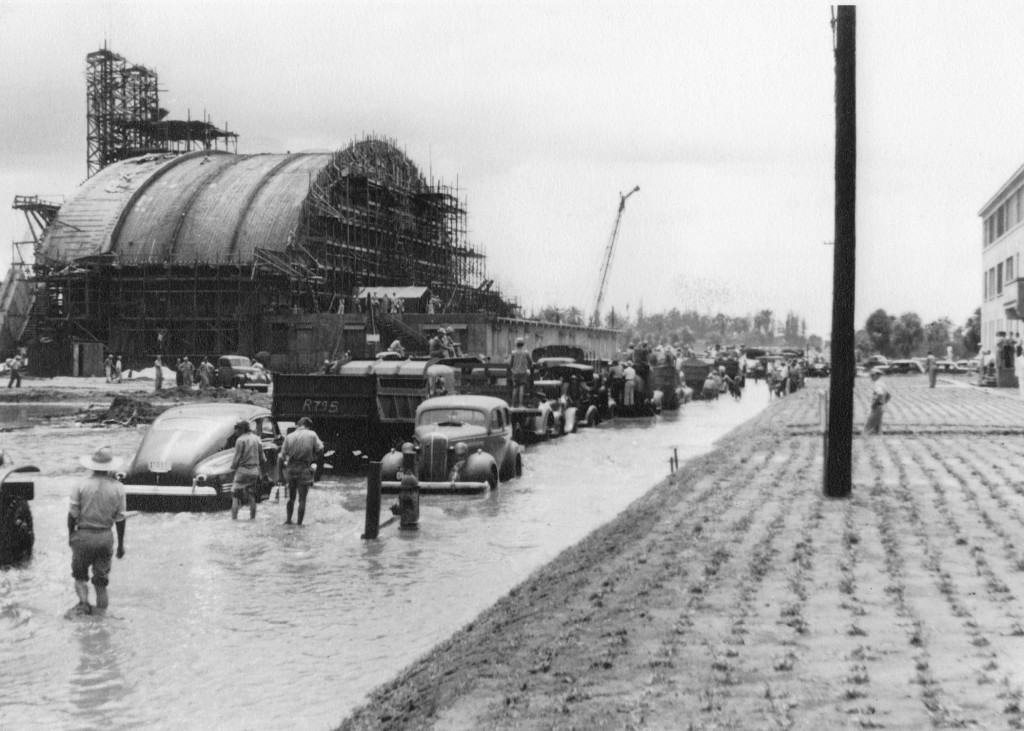 Hangar 5 under construction at Borinquen Field, Puerto Rico, 1941. Note the flooded roadway and crops planted alongside the road.