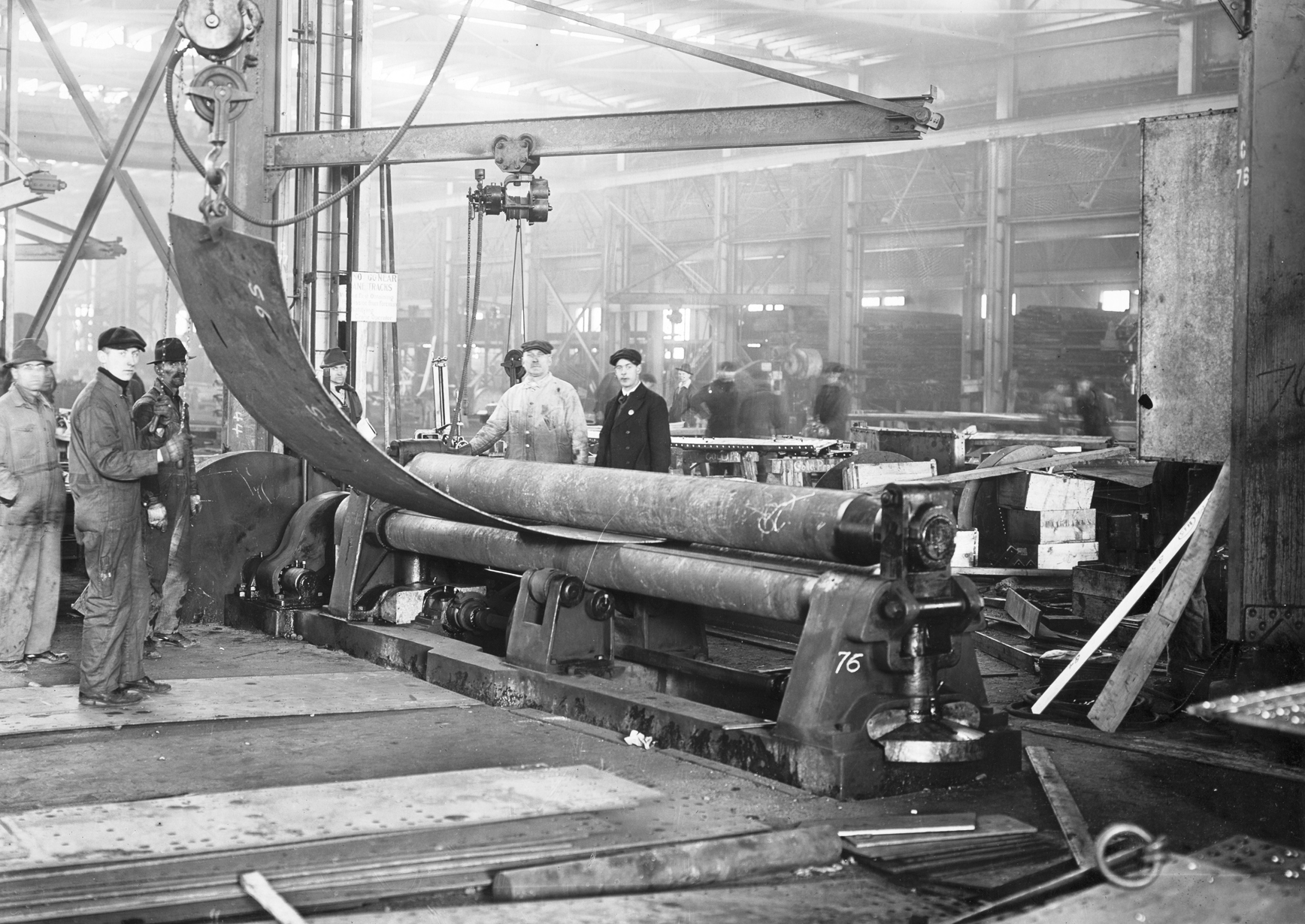 Shipfitters in one of the shops at the Puget Sound Naval Shipyard, Bremerton, Washington, United States rolling steel plate with assistance from the overhead jib crane, 1918.