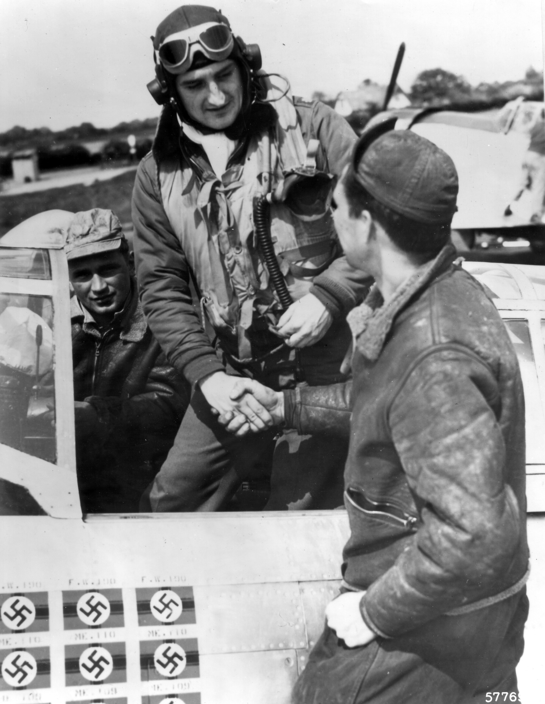 Lieutenant Colonel Francis Gabreski shaking hands with his crew chief Staff Sergeant Ralph Safford and his assistant crew chief Felix Schacki (background) before a mission, Jun 1944