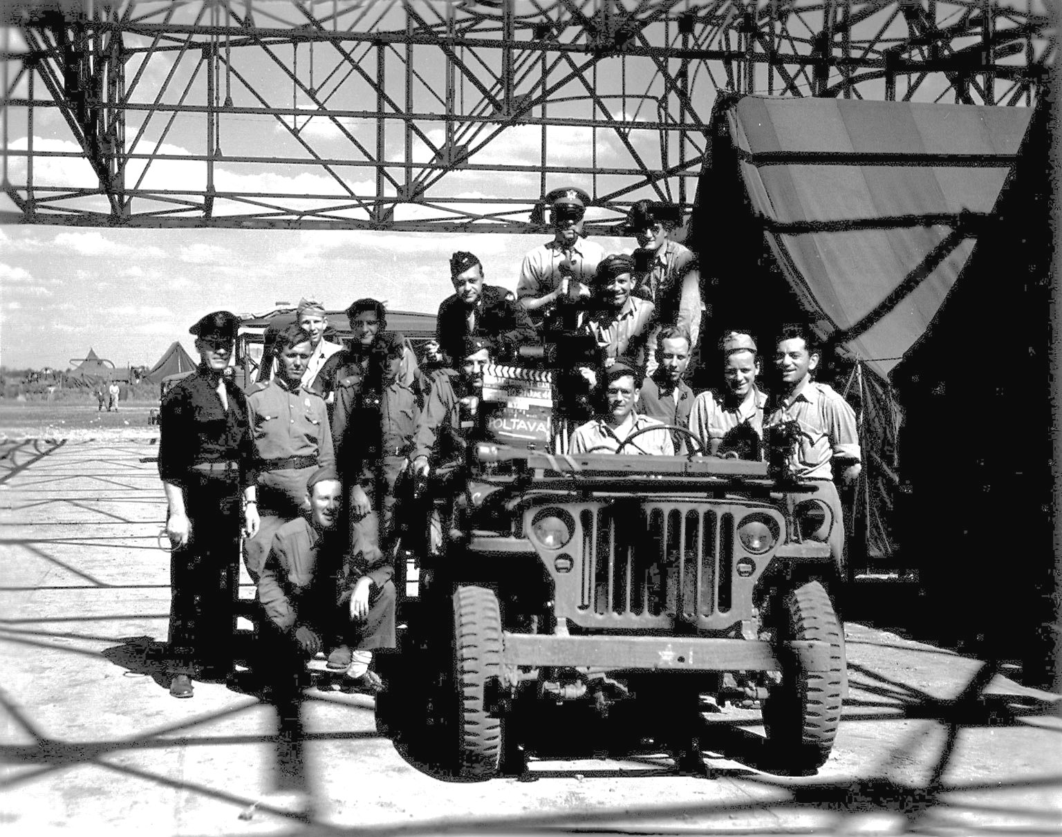 American and Soviet servicemen crowd around a Jeep at Poltava air base, Ukraine during Operation Frantic, 21 Jun 1944.