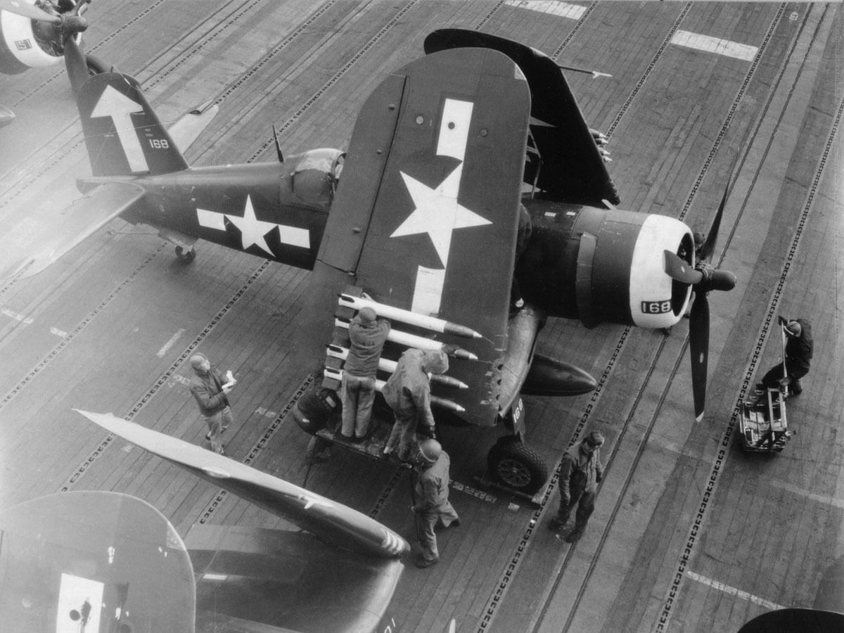 Vought F4U-1D Corsair of Marine Fighting Squadron VMF-451 ‘Blue Devils’ with its wings folded aboard USS Bunker Hill, south of Japan, spring 1945. Note the armorers readying the HVAR rockets and the rocket rack at right