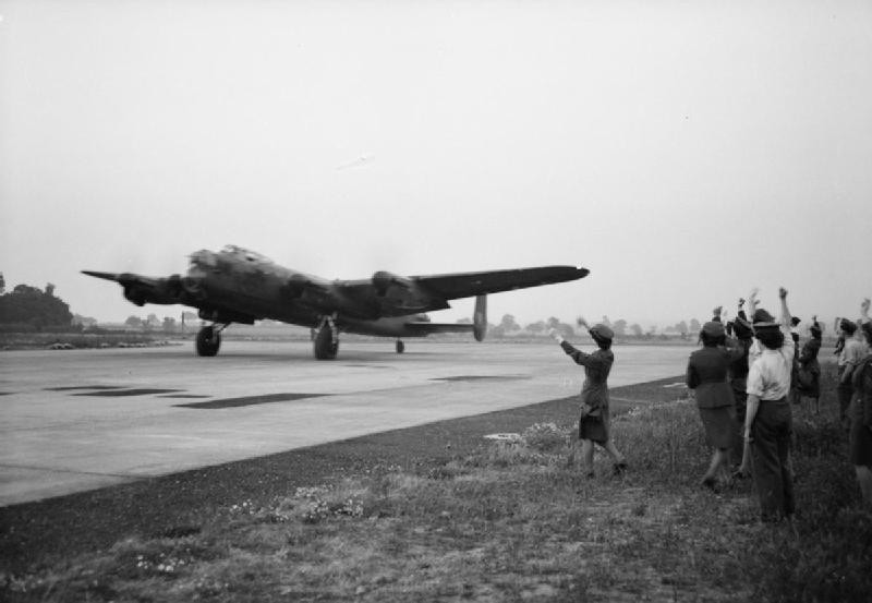 WAAF personnel and ground crew members waving off Pilot Officer W. H. Eager RCAF and his crew of a Lancaster B Mark I bomber of No. 61 Squadron RAF, RAF Syerston, Flintham, Nottinghamshire, England, United Kingdom, 1942-1943; this bomber was later lost during a raid on Mannheim, Germany on 10 Aug 1943
