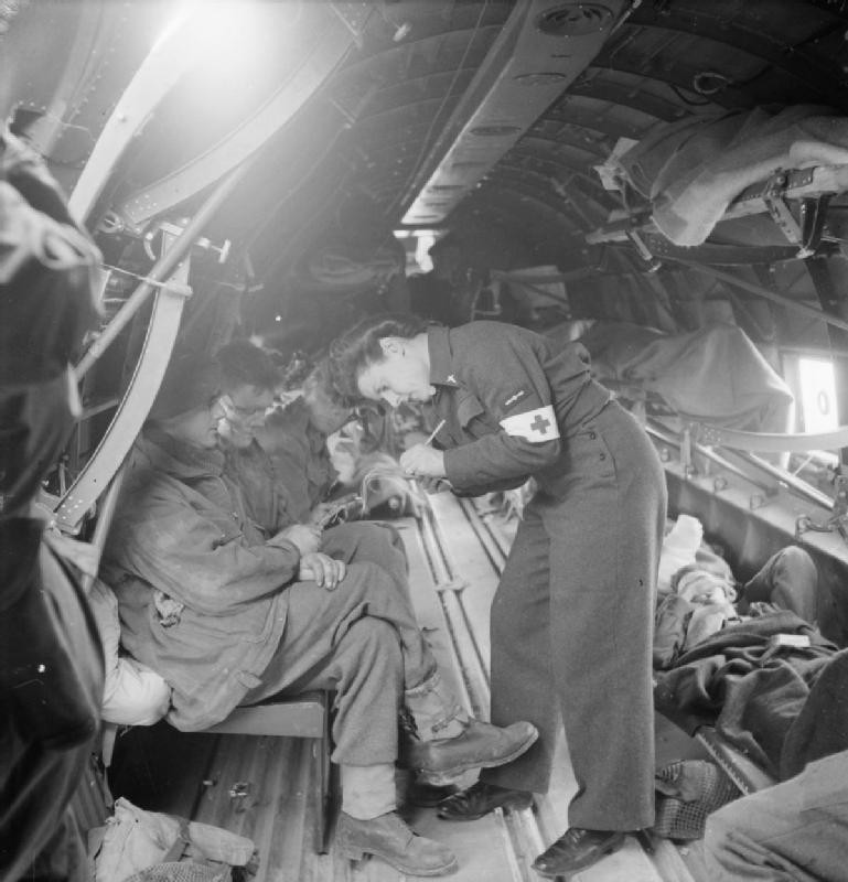WAAF Leading Aircraftwoman Pearl Bradburn writing out medical transport tags for a wounded soldier aboard a Dakota aircraft at B-2 Bazenville Advanced Landing Ground, Normandy, Jun-Aug 1944