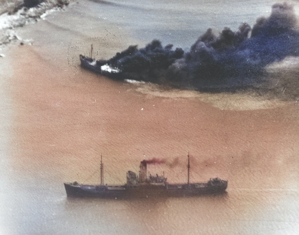 Japanese freighters Shoei Maru beached and burning and Takebe Maru damaged and trailing oil on the coast of French Indochina (Vietnam) north of Qui Nhon after being attacked by 175 USN carrier planes, 12 Jan 1945. [Colorized by WW2DB]