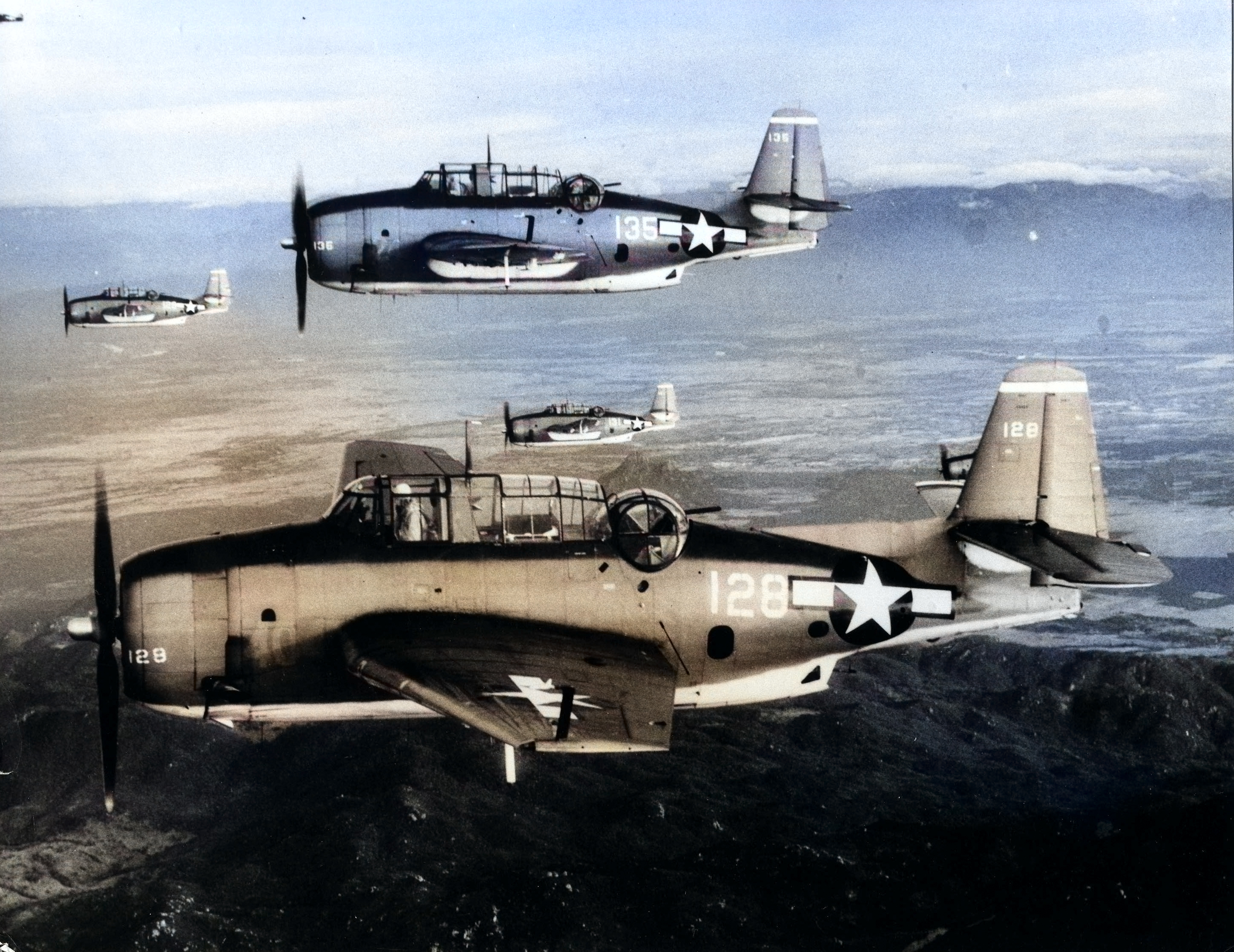 Four TBM Avengers of Torpedo Squadron 4 flying from the USS Essex on their way to strike targets along the coast of French Indochina (now Vietnam), 12 Jan 1945. [Colorized by WW2DB]