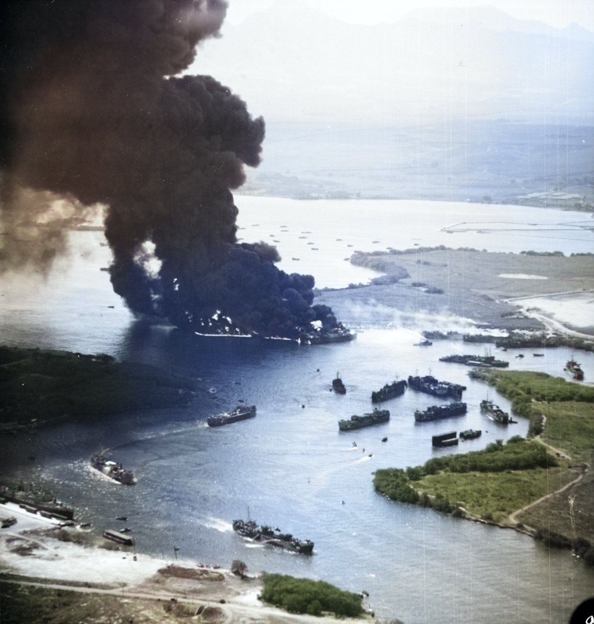 Fully laden United States Navy LSTs burning furiously while other ships flee in Pearl Harbor’s West Loch after massive chain-reaction explosions in what became known as the West Loch Disaster, 21 May 1944. [Colorized by WW2DB]