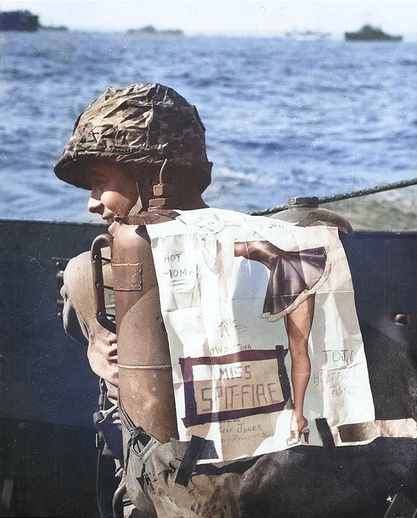 US Marine Private Kenneth R. Hager with his pin-up decorated flamethrower pack, off Iwo Jima, Feb 1945 [Colorized by WW2DB]