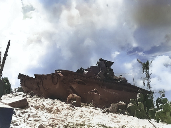 Using an Amtrac as shelter, American Marines fought on the beaches of Peleliu, Palau Islands, 15 Sep 1944 [Colorized by WW2DB]